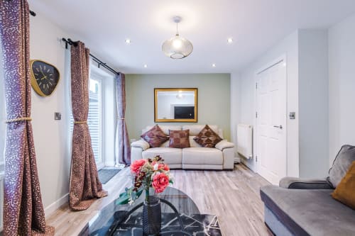 Modern living room at Vidale Court villa in Manchester with cream sofa, patterned curtains, and contemporary furnishings