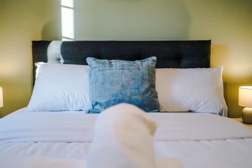 Modern bedroom with black headboard, white bedding, blue accent pillow at Vidale Court villa in Manchester