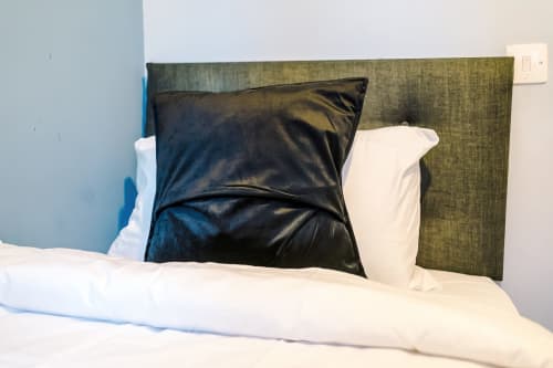 Bed with olive green headboard, black and white pillows at Vidale Court villa in Manchester