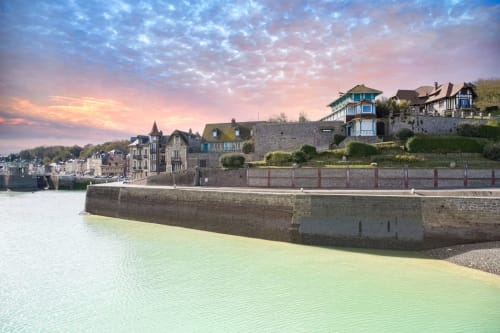 Vue pittoresque du port de Saint-Valery-en-Caux avec fortifications en pierre et bâtiments historiques au coucher de soleil