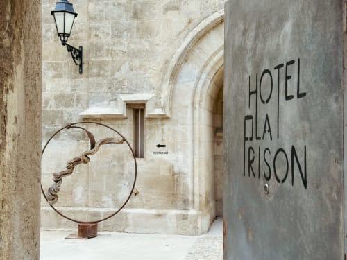 Entrada del Hotel Glai Risoan en Béziers con arco de piedra, lámpara de hierro y escultura decorativa