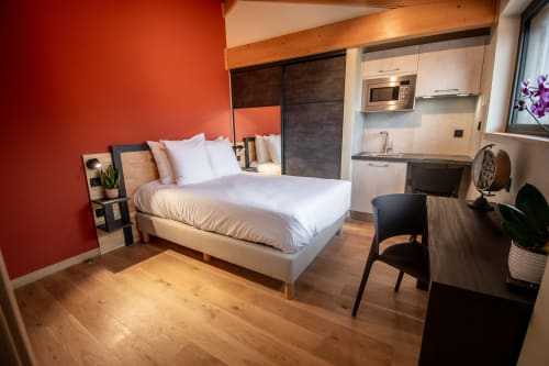 Studio au Lieu-dit Boulage avec lit, kitchenette, bureau et mur d'accent orange