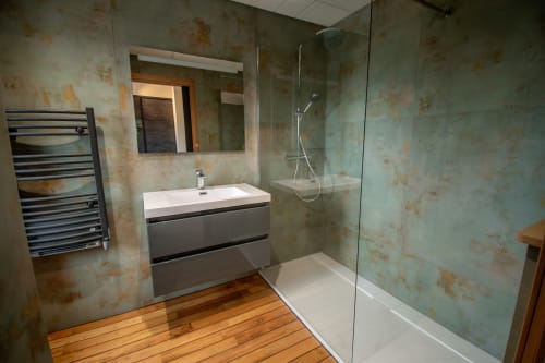 Modern bathroom at Lieu-dit Boulage with walk-in shower, floating vanity, heated towel rack, and wooden flooring