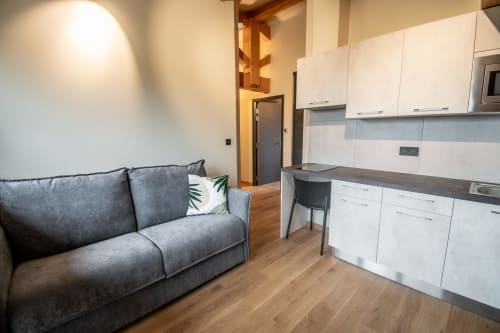 Studio moderne à Lieu-dit Boulage avec canapé gris, cuisine blanche, parquet et coin repas