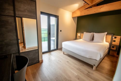 Chambre moderne à Lieu-dit Boulage, Marquefave avec lit blanc, mur d'accent vert, poutres en bois et accès à la terrasse