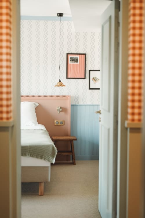 Chambre accueillante à l'Hôtel Saint Enogat à Dinard avec papier peint ondulé, tête de lit corail, lampe suspendue et œuvres encadrées