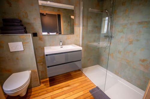 Modern bathroom at Lieu-dit Boulage with wooden flooring, gray vanity, walk-in shower, and tiled walls