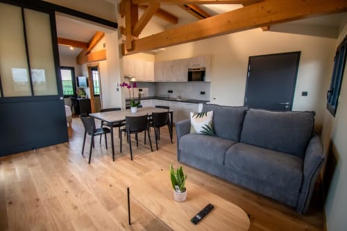 Modern open-plan apartment at Lieu-dit Boulage with gray sofa, dining table, and light wood flooring in Marquefave