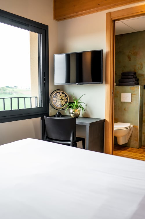 Premium apartment bedroom with wall-mounted TV, desk, clock and plant at Lieu-dit Boulage hotel in Marquefave