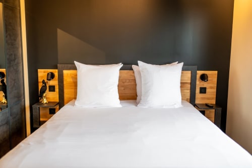 Modern bedroom at Lieu-dit Boulage hotel in Marquefave with white bedding, wooden nightstands, and dark accent wall