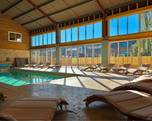 Piscine couverte de Domaine Les Racines B&B avec chaises longues et grandes baies vitrées donnant sur Croix-Moligneaux