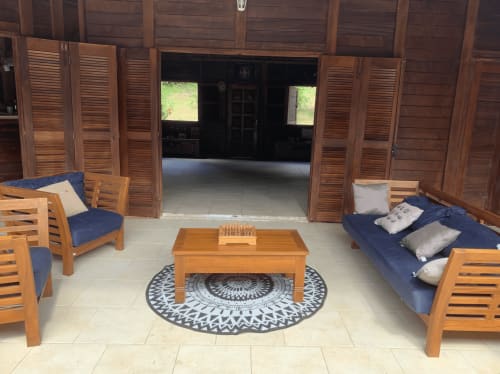 Salon Riviera BnB avec mobilier en bois, coussins bleus et tapis géométrique à Rivière Salée