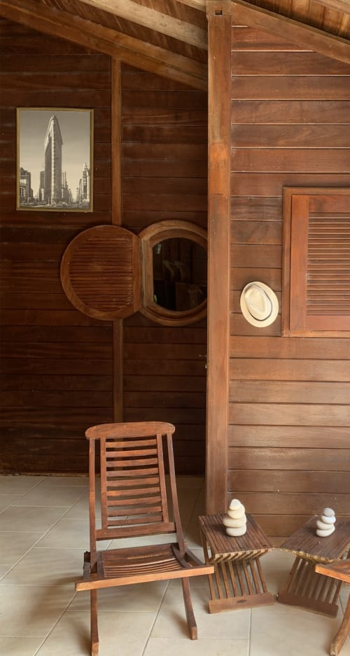 Intérieur de sauna en bois au Riviera bnb à Rivière Salée avec chaise longue, porte-chapeaux et photographie du Flatiron building