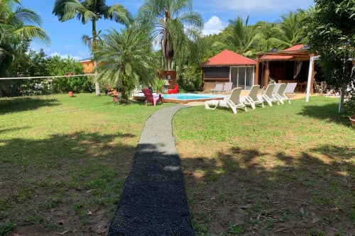 Jardin avec piscine du Riviera BnB à Rivière Salée, transats, palmiers et décor tropical