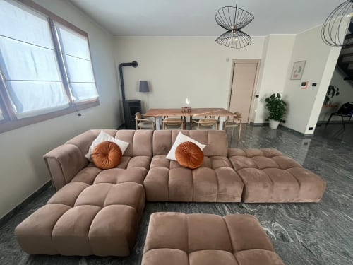 Soggiorno moderno con divano modulare rosa, tavolo da pranzo in legno e lampade a sospensione nell'appartamento Casa Vacanze Luna, Seriate