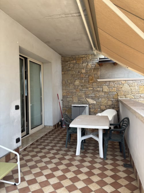 Terrazza coperta di Casa Vacanze Luna con tavolo da pranzo, sedie e parete in pietra a Seriate, Italia