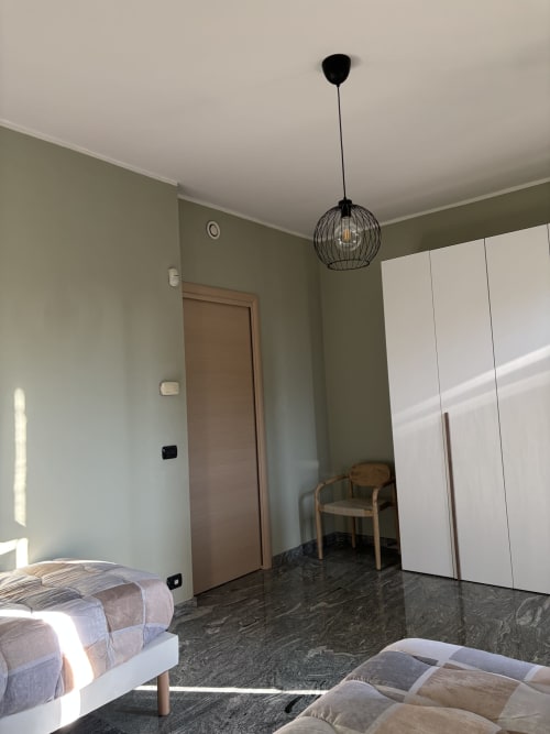 Camera moderna presso Casa Vacanze Luna a Seriate con illuminazione a sospensione, guardaroba bianco e vista sul giardino