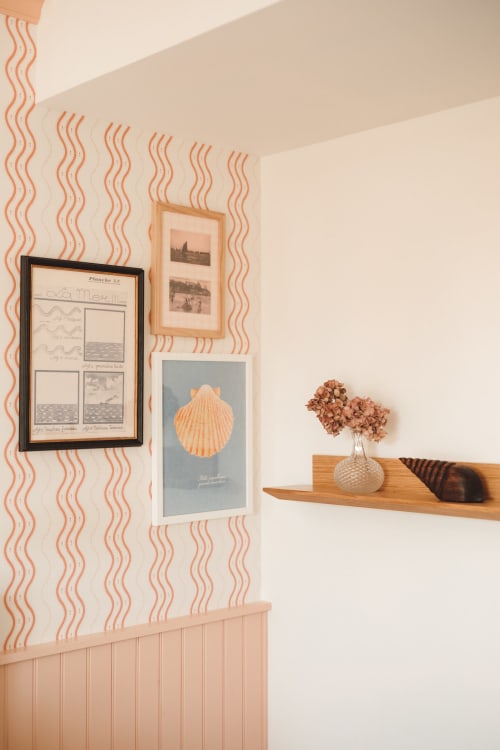 Détail de chambre à l'Hôtel Saint Enogat avec papier peint ondulé, art côtier encadré et étagère en bois ornée de fleurs séchées à Dinard