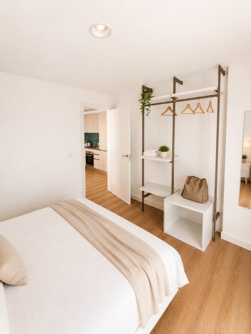 Modernes Schlafzimmer mit offener Küche im Apartment Fly High, Morro Jable, mit Bett, Kleiderständer und Meerblick