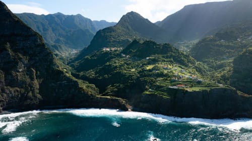 Falésias dramáticas e oceano turquesa no Refúgio do Nevoeiro, Porto Moniz, Portugal com vales exuberantes