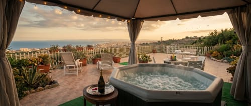 Lussuosa terrazza con vasca idromassaggio con vista su Aci Castello e il Mar Ionio al tramonto