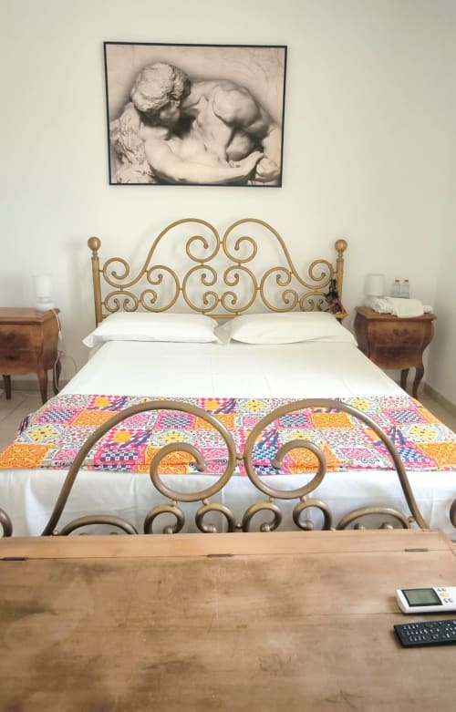 Camera elegante presso il Pupi Catania Etna Farm B&B con letto in ottone ornamentale, biancheria bianca e coperta patchwork colorata ad Aci