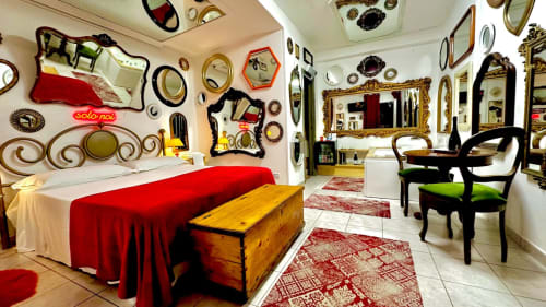 Camera eclettica presso la Pupi Catania Etna Farm B&B con letto rosso, pareti specchiate, specchi decorativi e sedie nere ad Aci