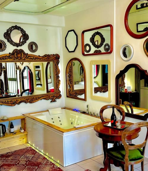 Bagno lussuoso presso il B&B Pupi Catania Etna Farm con specchi ornati, vasca idromassaggio e eleganti arredi in legno ad Aci
