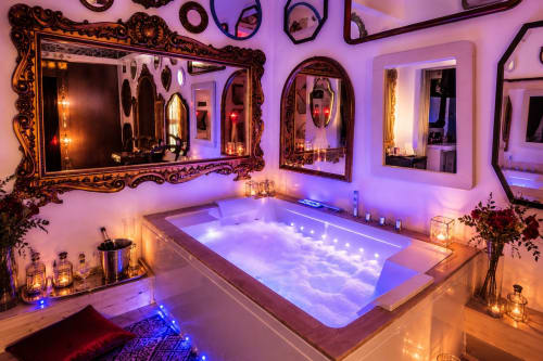 Lussuoso bagno spa con vasca idromassaggio illuminata, specchi ornamentali e illuminazione ambientale viola presso Pupi Catania B&B ad Aci