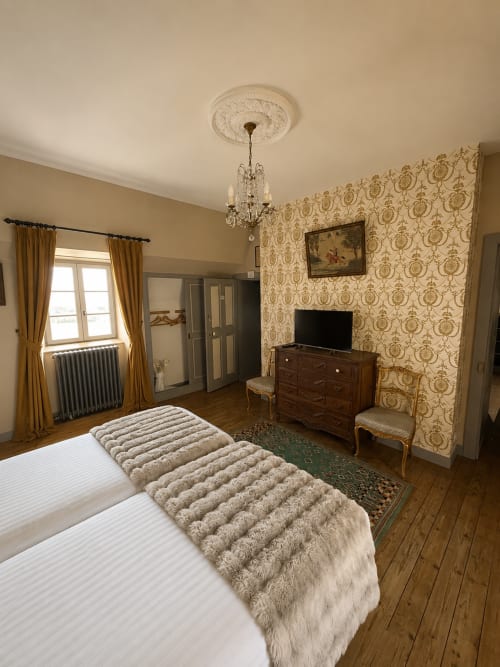 Chambre twin au Château De Montbrault avec décor élégant d'époque, papiers peints ornés, commode en bois et vue sur le jardin