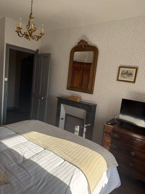 Chambre familiale du Château De Montbrault avec lit, miroir en bois, cheminée et mobilier d'époque