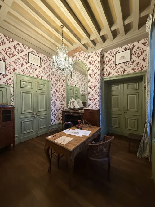Élégante chambre du XVIIIe siècle au Château de Montbrault avec papier peint damas bordeaux, portes vertes, lustre en cristal et
