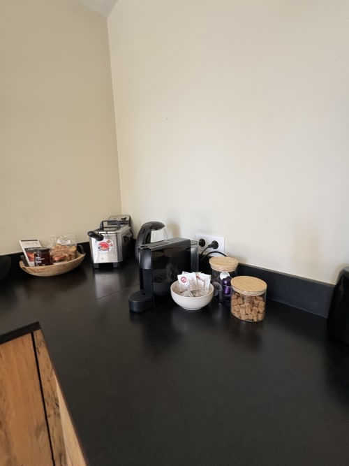 Plan de travail de cuisine avec cafetière, bouilloire électrique et boîtes de rangement à la Conciergerie Maurin à Arles