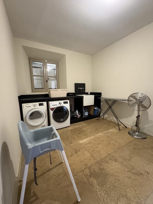 Buanderie de la Conciergerie Maurin avec lave-linge, sèche-linge, station de repassage et ventilateur à Arles