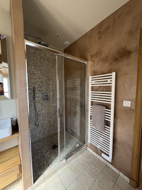 Salle de bains moderne à la Conciergerie Maurin à Arles avec douche italienne, sèche-serviettes chauffant et murs texturés marron