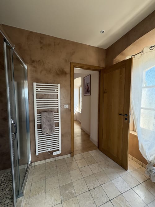 Salle de bain moderne du Mas en Camargue à Arles avec murs accentués marron, sèche-serviettes blanc chauffant et carrelage