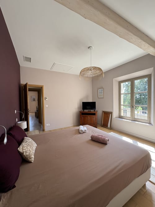 Chambre spacieuse au Mas en Camargue, Conciergerie Maurin à Arles avec lit king-size, luminaire suspendu en rotin, plafond à poutres apparentes