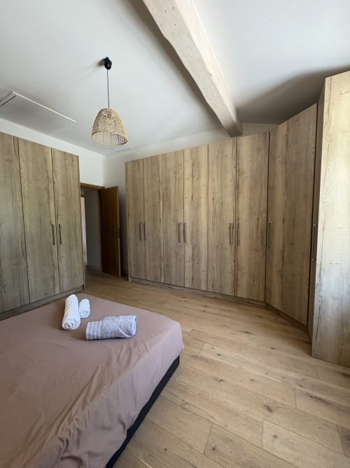 Chambre spacieuse à la Conciergerie Maurin à Arles avec armoires en bois, lit garni de serviettes et parquet