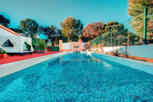 Piscina do Chalet Do Lago com azulejos turquesa, deck vermelho, espreguiçadeiras brancas e árvores sob céu limpo em Montargil, Portugal