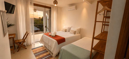 Quarto moderno da Vila Pitangueira em Uruçuca com duas camas, varanda com vista para o jardim e decoração contemporânea