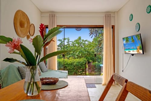 Apartamento Verde Vila Pitangueira com vista para piscina, área de refeições, flores tropicais e acesso ao pátio em Uruçuca