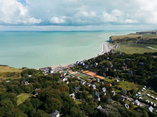 Vue aérienne du village côtier de Saint-Valery-en-Caux avec baie turquoise, falaises et paysage verdoyant