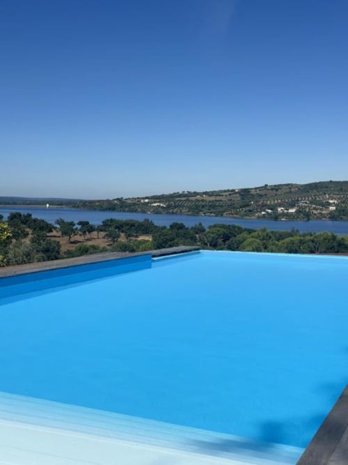 Piscina infinita com vista para o Lago de Montargil na Monte da Tojeirinha, Portugal, entre oliveiras e céu azul cristalino
