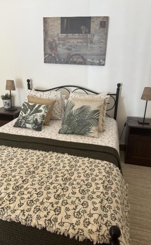 Quarto aconchegante no Monte da Tojeirinha B&B em Montargil com roupa de cama estampada, almofadas decorativas, luminárias de cabeceira e bicicleta