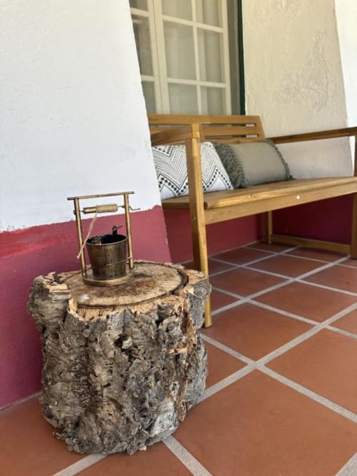 Poço rústico de madeira no pátio com azulejos vermelhos em Monte da Tojeiranha, Portugal, com banco de madeira e parede vermelha
