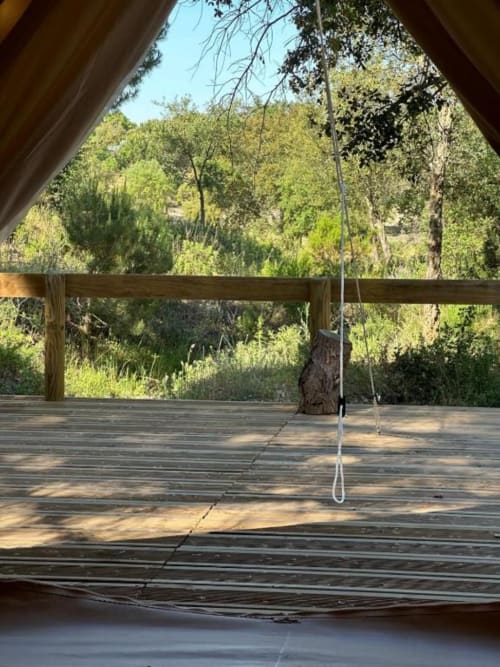 Tenda de madeira no Monte da Tojeirinha com balanço suspenso, vista para floresta verde e lago em Montargil, Portugal