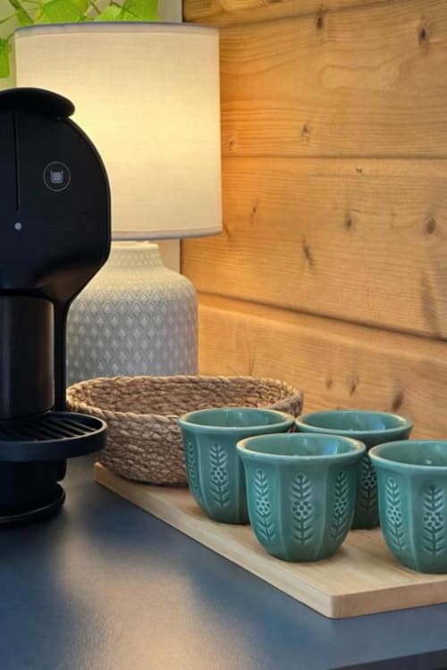 Cafeteira, xícaras de cerâmica teal e cesta tecida na prateleira de madeira do bungalow Monte da Tojeirinha em Montargil
