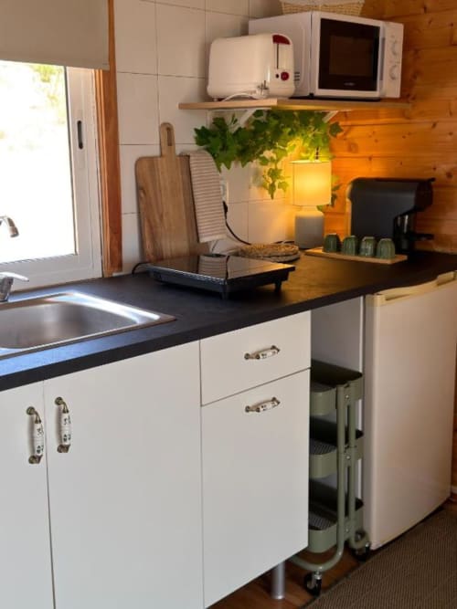 Cozinha moderna em Monte da Tojeiranha com armários brancos, bancada preta, micro-ondas e iluminação aconchegante com vista para