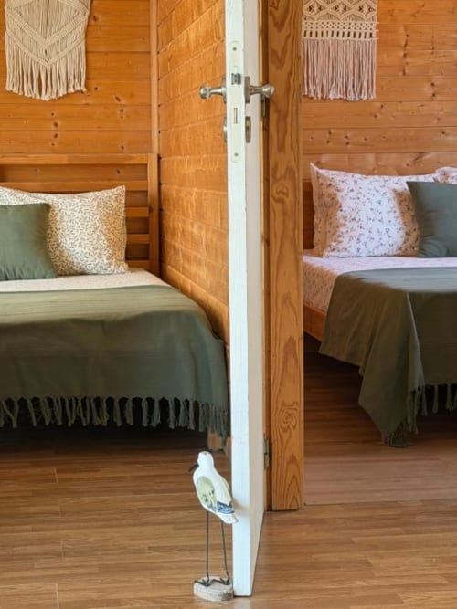 Interior do bungalow de dois quartos em Monte da Tojeirinha com paredes em madeira, camas twin e vista para o lago em Montargil
