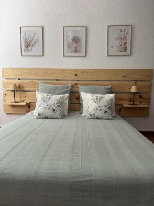 Quarto moderno com cabeceira em madeira, roupa de cama listrada e arte botânica na parede da quinta Monte da Tojeiranha em Montargil